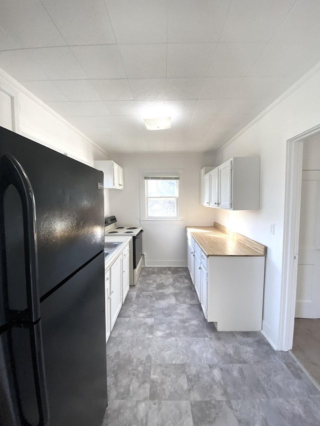 kitchen with white cabinetry, wooden counters, black refrigerator, ornamental molding, and white range with electric stovetop