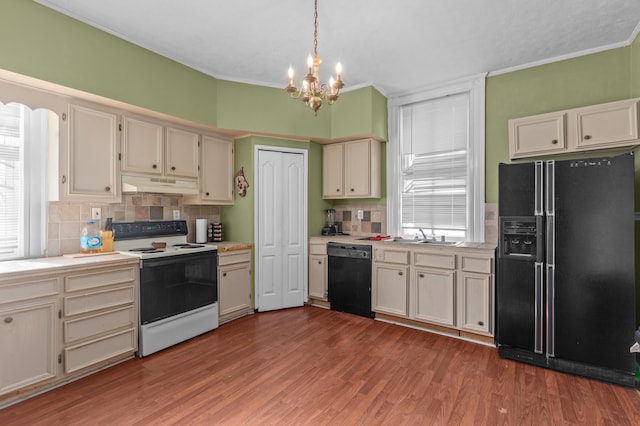 kitchen with pendant lighting, wood-type flooring, tasteful backsplash, and black appliances