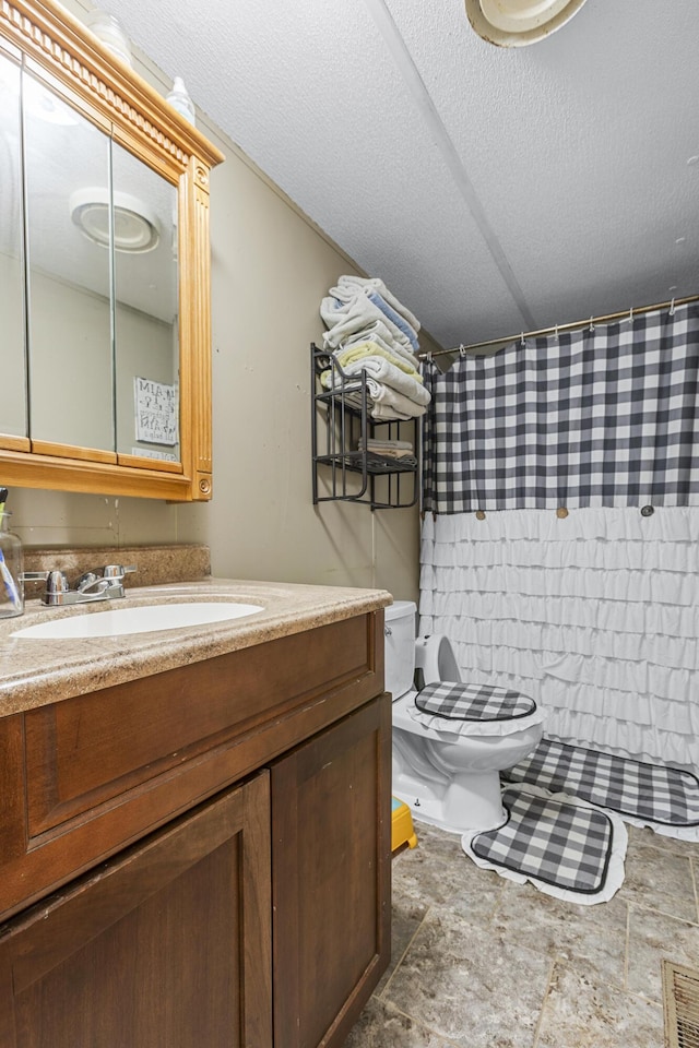 bathroom featuring vanity, walk in shower, a textured ceiling, and toilet