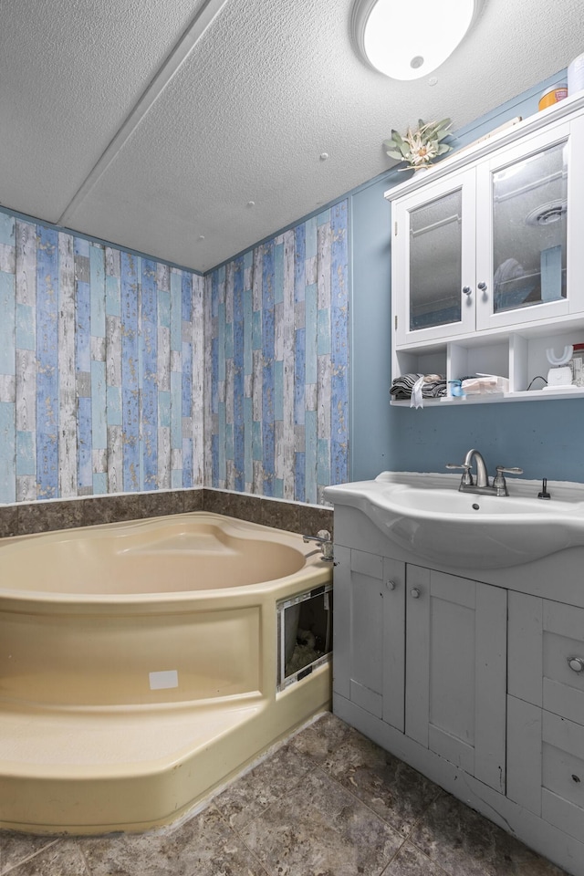 bathroom featuring vanity, a tub to relax in, and a textured ceiling