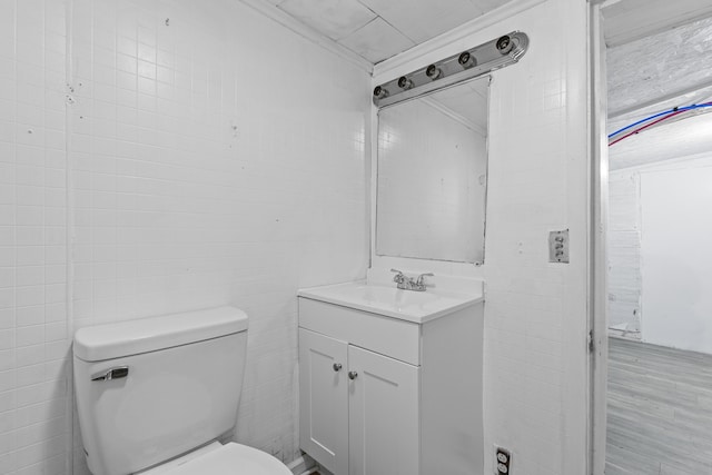 bathroom with vanity, toilet, and tile walls