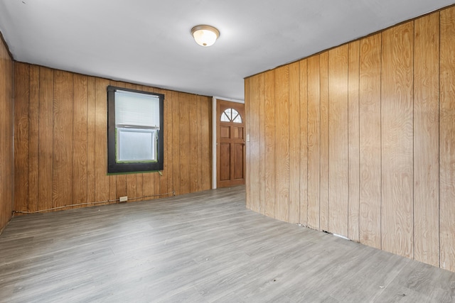 empty room featuring wood walls and light wood-type flooring