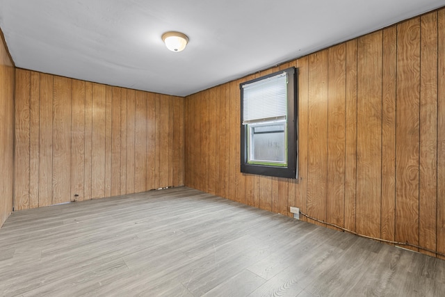 spare room with wooden walls and light wood-type flooring