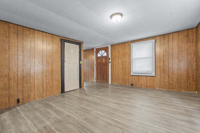 empty room with light hardwood / wood-style flooring and wood walls