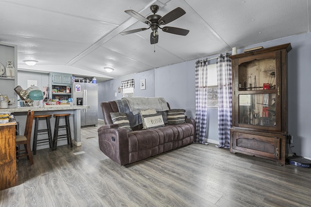 living room with hardwood / wood-style flooring, ceiling fan, vaulted ceiling, and a textured ceiling