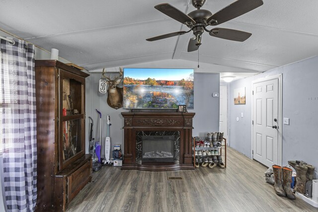 unfurnished living room featuring hardwood / wood-style flooring, vaulted ceiling, ceiling fan, and a high end fireplace