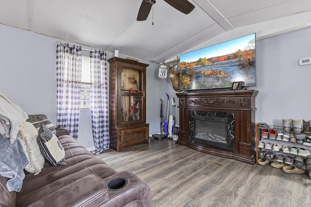 living room with hardwood / wood-style floors, vaulted ceiling, a premium fireplace, and ceiling fan