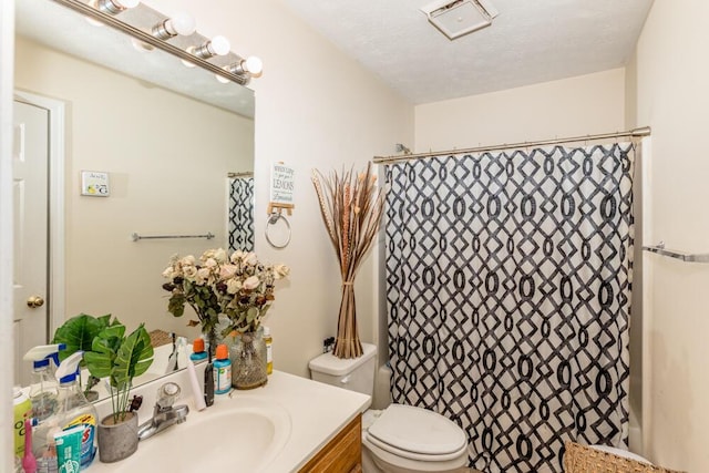 bathroom with walk in shower, vanity, toilet, and a textured ceiling