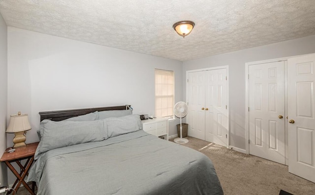 carpeted bedroom featuring a textured ceiling and two closets