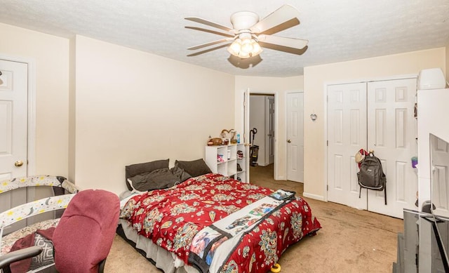 carpeted bedroom featuring ceiling fan, a closet, and a textured ceiling