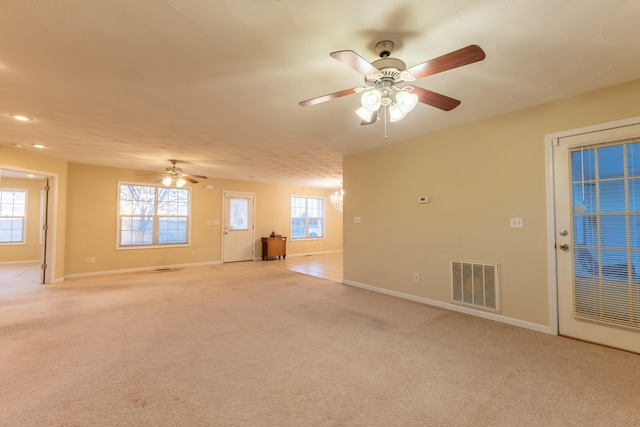 spare room featuring ceiling fan, light colored carpet, and a wealth of natural light