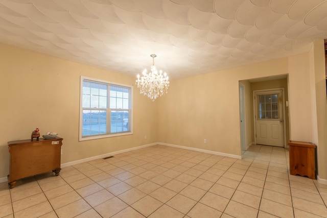 tiled spare room with an inviting chandelier