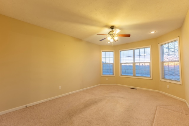 carpeted spare room featuring ceiling fan and plenty of natural light