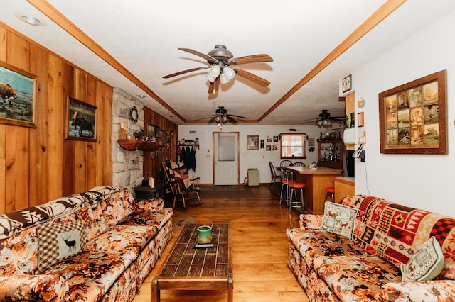 living room featuring ceiling fan, wooden walls, hardwood / wood-style floors, and a textured ceiling