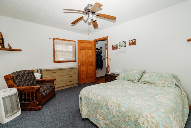 bedroom featuring ceiling fan, dark carpet, and heating unit