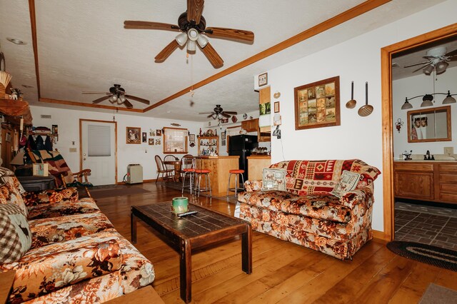 living room featuring ceiling fan, wood-type flooring, and a textured ceiling