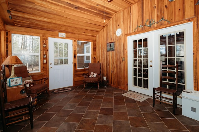 entryway featuring wood walls, lofted ceiling, dark tile patterned floors, wooden ceiling, and french doors