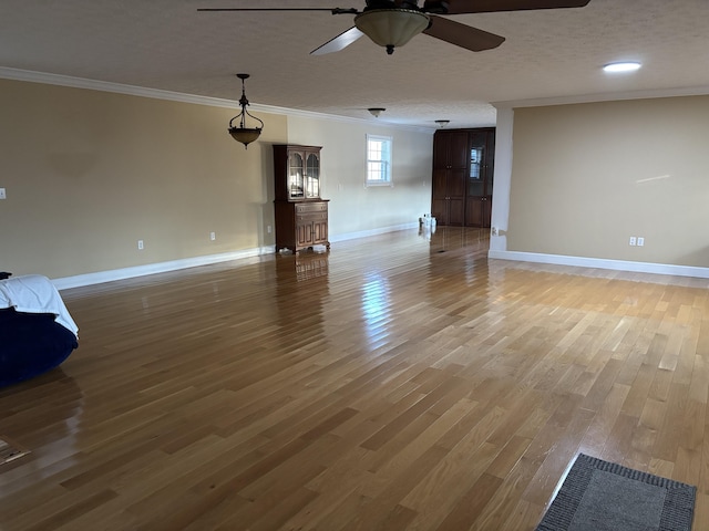 unfurnished living room with wood-type flooring, ornamental molding, ceiling fan, and a textured ceiling