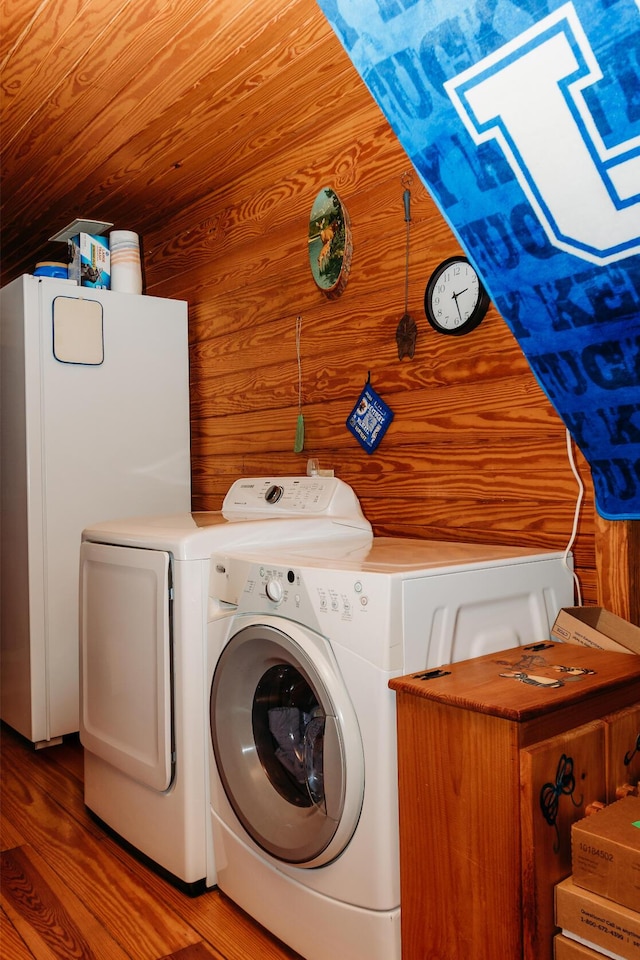 clothes washing area featuring hardwood / wood-style floors, wooden walls, a skylight, independent washer and dryer, and wooden ceiling