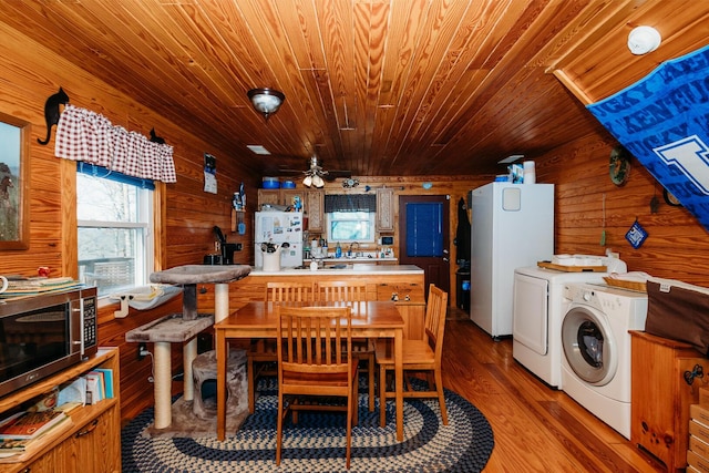 dining space with washer and clothes dryer, ceiling fan, wood-type flooring, wooden ceiling, and wood walls