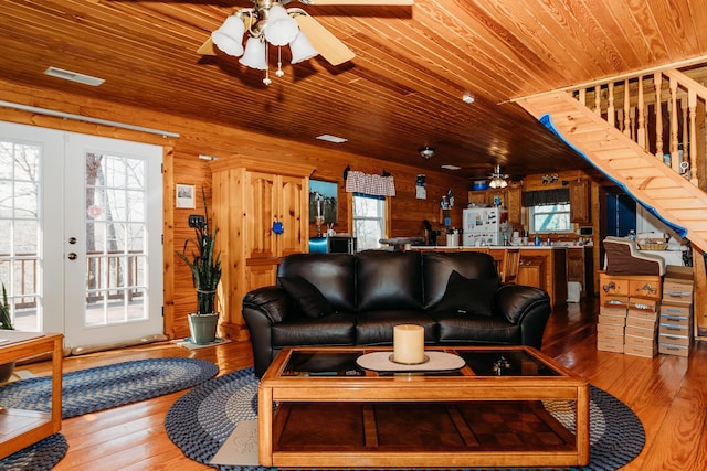 living room featuring wooden walls, wood-type flooring, ceiling fan, wooden ceiling, and french doors