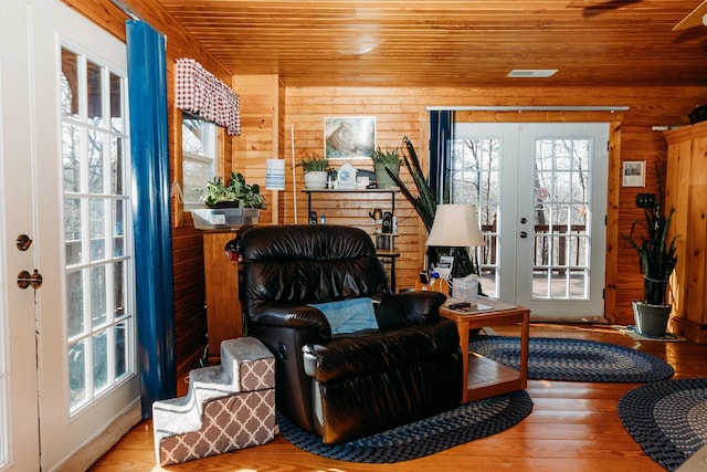 sitting room featuring wood ceiling, wooden walls, hardwood / wood-style floors, and french doors