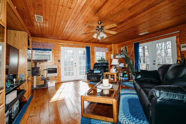 living room featuring plenty of natural light, heating unit, light hardwood / wood-style floors, and french doors