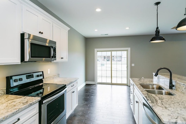 kitchen featuring decorative light fixtures, sink, white cabinets, light stone counters, and stainless steel appliances