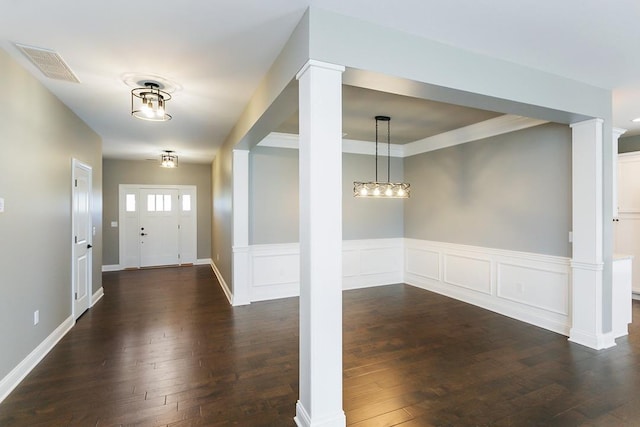 foyer featuring crown molding, dark wood-type flooring, and decorative columns