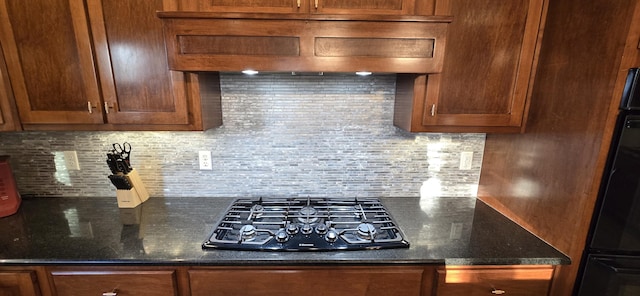 kitchen featuring custom exhaust hood, oven, dark stone counters, black gas stovetop, and decorative backsplash