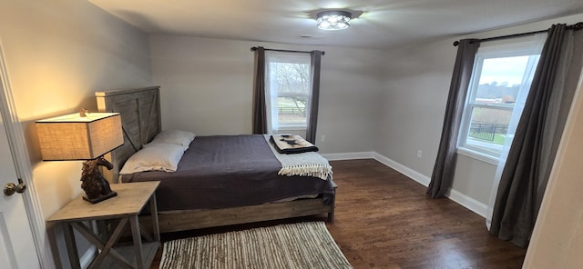 bedroom with multiple windows and dark hardwood / wood-style floors