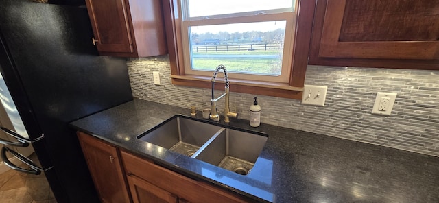 kitchen featuring tasteful backsplash, sink, a healthy amount of sunlight, and black fridge