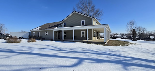 snow covered back of property featuring a porch