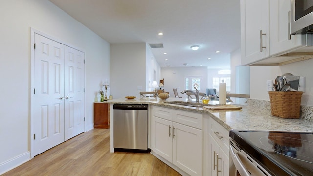 kitchen featuring sink, white cabinetry, light stone counters, appliances with stainless steel finishes, and light hardwood / wood-style floors