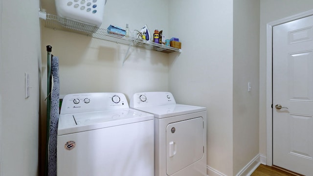 clothes washing area with hardwood / wood-style flooring and washer and dryer