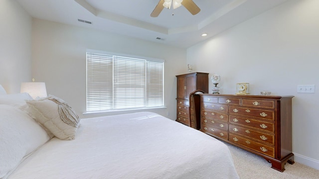 carpeted bedroom with ceiling fan and a tray ceiling