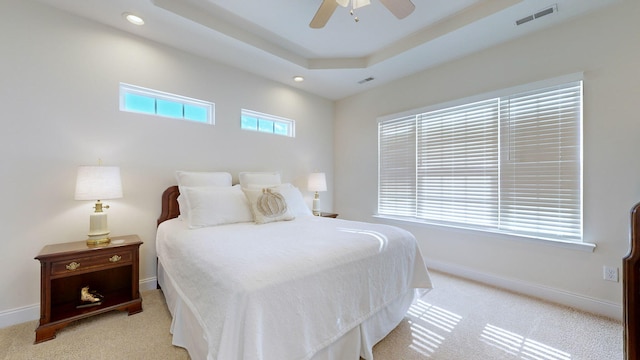 bedroom featuring light colored carpet, ceiling fan, and a tray ceiling