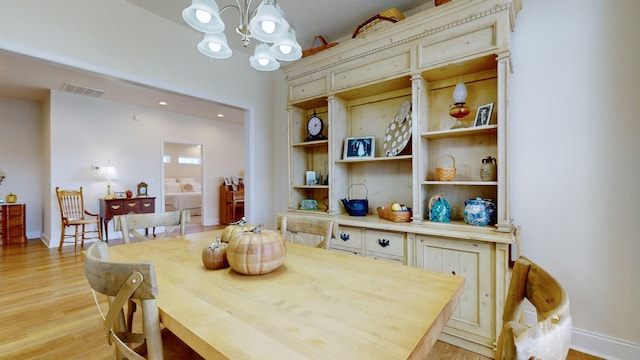 dining area featuring an inviting chandelier, built in features, and light wood-type flooring