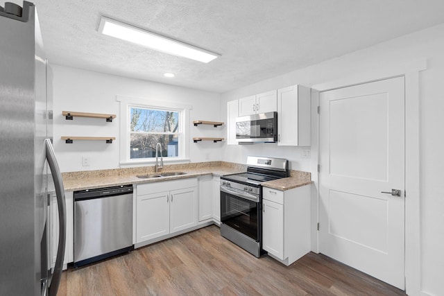 kitchen featuring white cabinetry, appliances with stainless steel finishes, sink, and light wood-type flooring