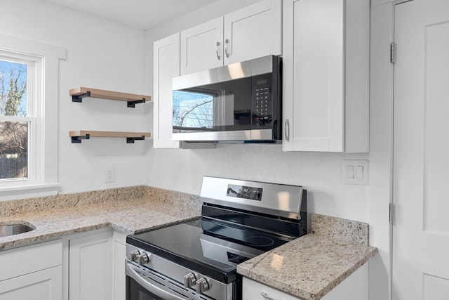 kitchen featuring stainless steel appliances, a healthy amount of sunlight, and white cabinets