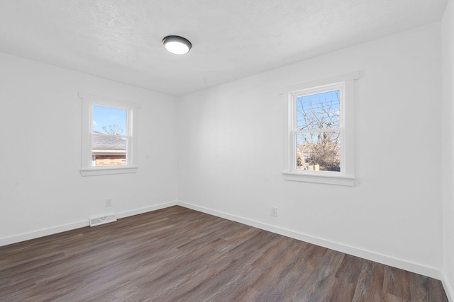 unfurnished room featuring a wealth of natural light, dark hardwood / wood-style floors, and a textured ceiling