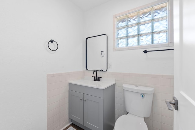 bathroom with vanity, tile walls, and toilet