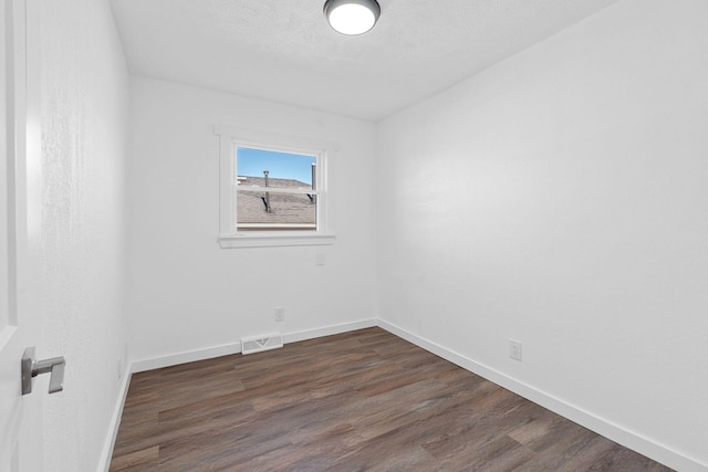 unfurnished room with dark hardwood / wood-style floors and a textured ceiling