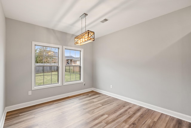 empty room with visible vents, light wood-style flooring, and baseboards