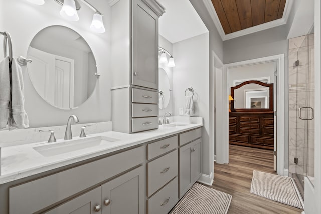 bathroom featuring double vanity, a shower stall, a sink, and wood finished floors