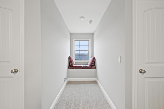 corridor with carpet, visible vents, and baseboards