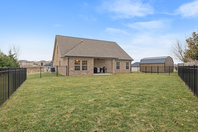 rear view of house with brick siding, a lawn, a fenced backyard, and roof with shingles