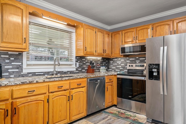 kitchen with sink, light stone counters, stainless steel appliances, crown molding, and light wood-type flooring