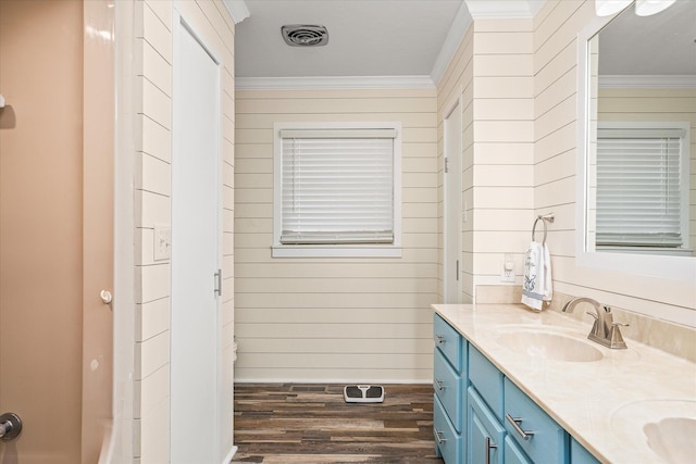 bathroom with ornamental molding, wood-type flooring, vanity, and wood walls