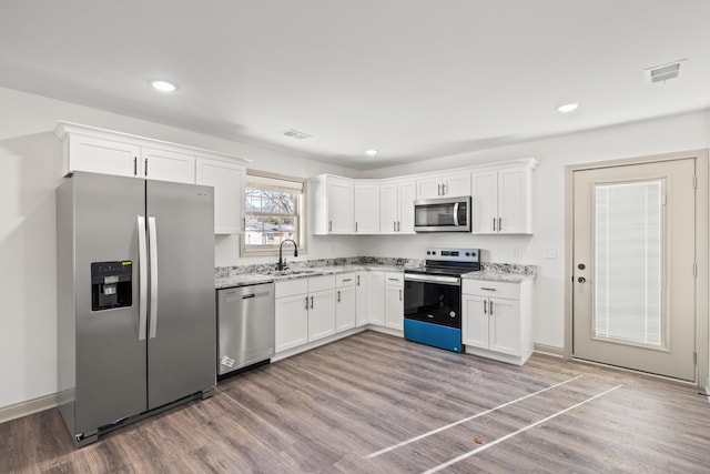 kitchen with white cabinetry, stainless steel appliances, light hardwood / wood-style floors, and sink